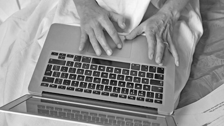 Close up photo of a laptop on someone's lap with their hands touching the keyboard