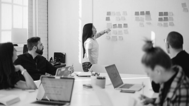 Woman at work placing sticky notes on a wall – by You X Ventures on Unsplash
